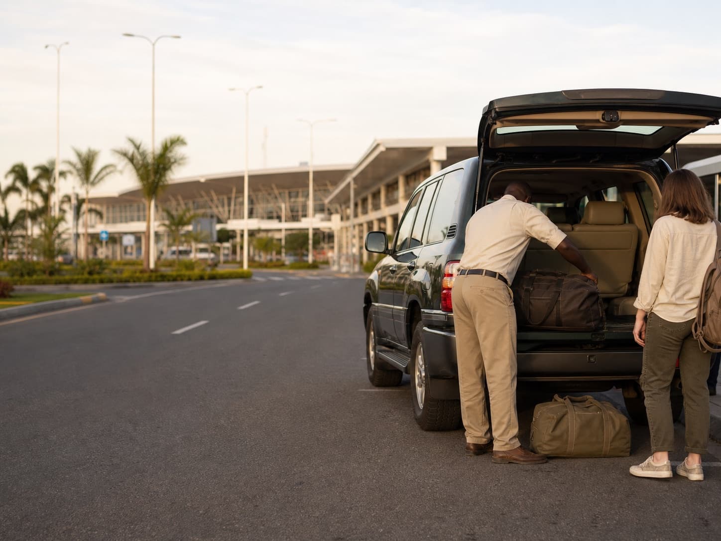 Driver loading luggage into an SUV outside an airport terminal